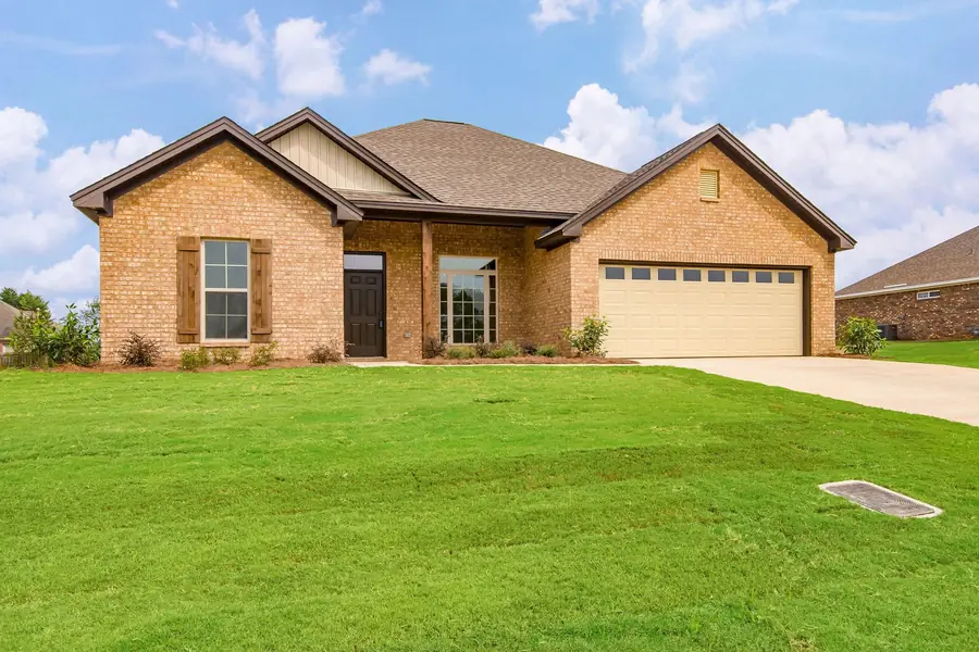 Tan brick home with an arched entry, brown shutters and a two-car garage in Deatsville, Alabama