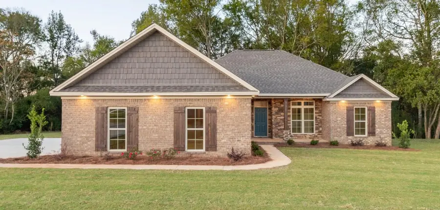 Brick home with shake-shingle gable and soffit lights glowing at dusk
