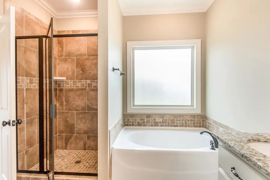 Primary bathroom with a tiled glass shower and a soaking tub under a window