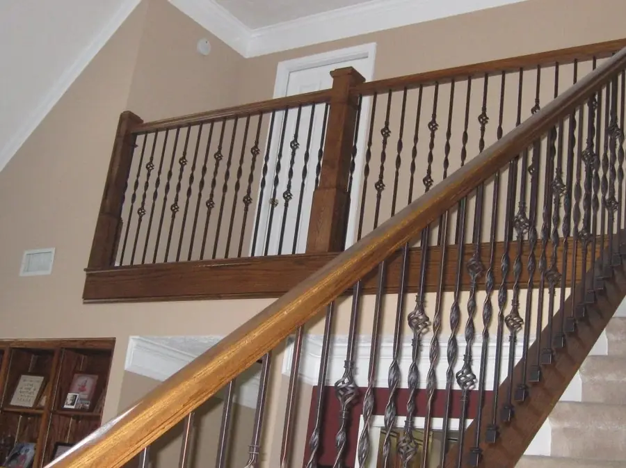 Staircase with a stained wood handrail and decorative wrought iron balusters