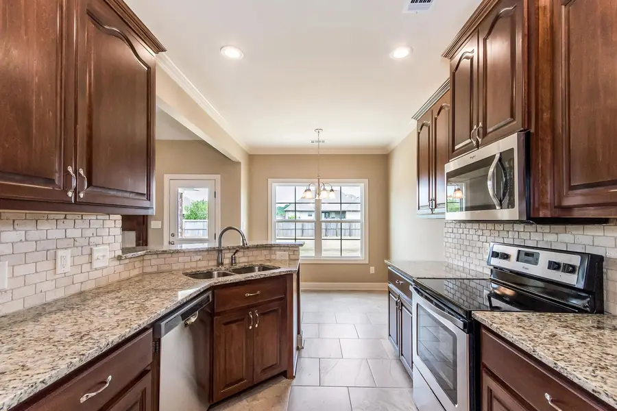 Kitchen with stained cabinets, granite counters, tile backsplash and stainless appliances