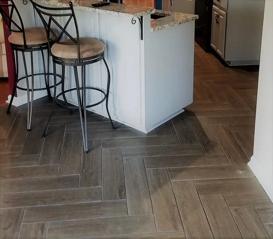Kitchen island with bar stools over wood-look herringbone tile floor